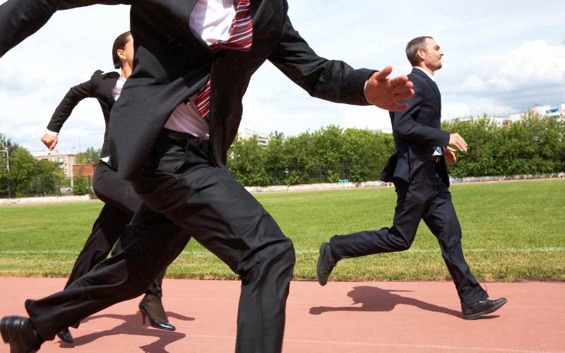 sales reps in suit run on a school running track